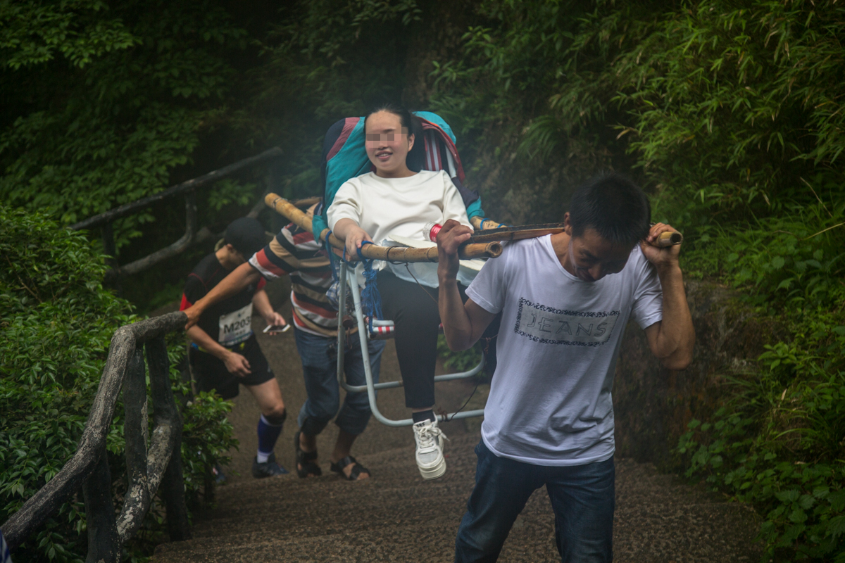 图为轿夫们正在抬着一位女士上山.