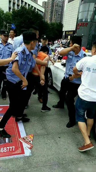 身穿城管制服的男子团队,围殴一穿商家t恤的学生模样年轻男子,一名