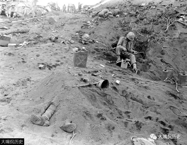 1945年2月硫磺岛,一名被打死的日军士兵尸体被埋在土堆中,旁边是美