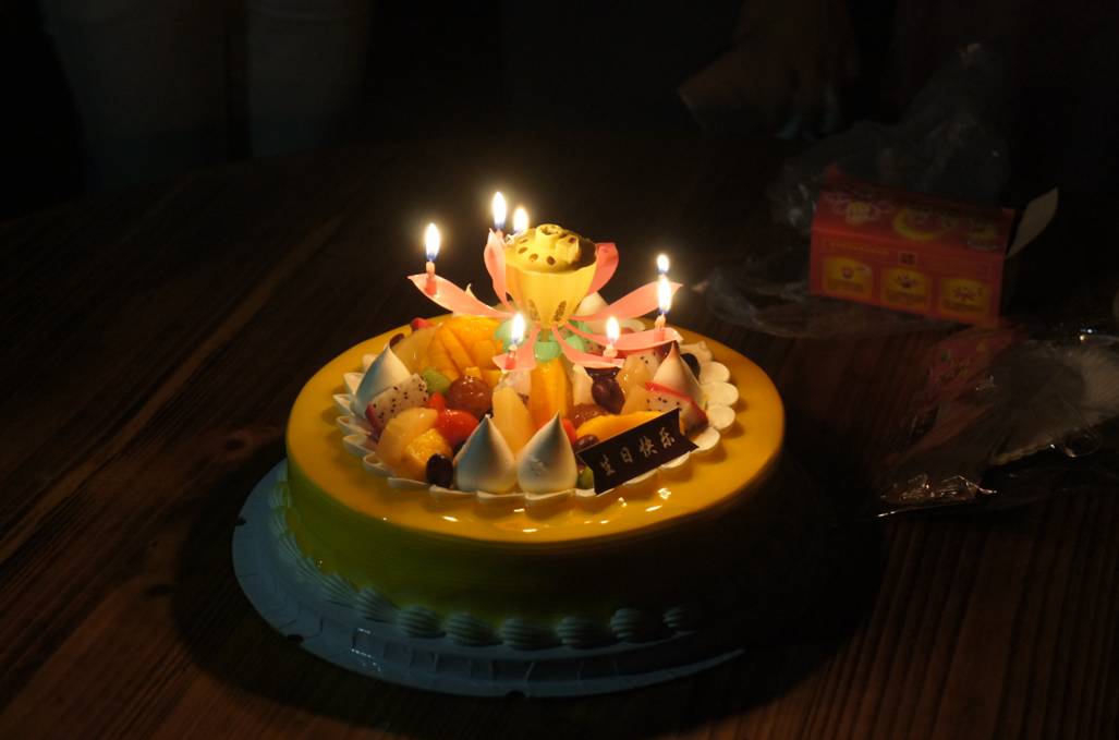 一个精美的生日蛋糕摆上餐桌,蜡烛闪亮,寓意浓浓的人文关怀.