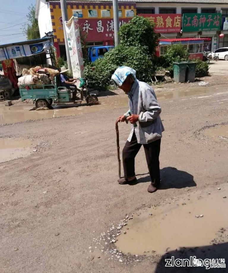 网爆:兰陵县手拄拐杖的老太太在泥泞的道路行走