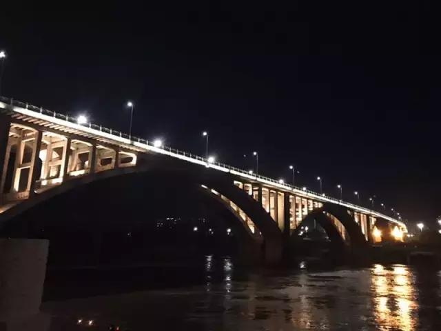 岷江大桥的夜景,暖暖的橙光倒映在水面,波光粼粼.