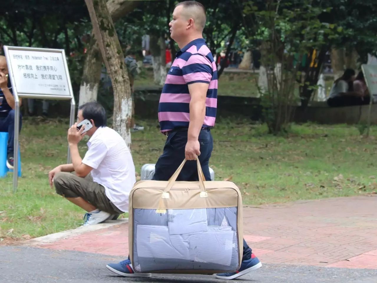 这位父亲肩膀上背着沉重的行李,在阳光下,微皱眉头四望,似乎在寻找着