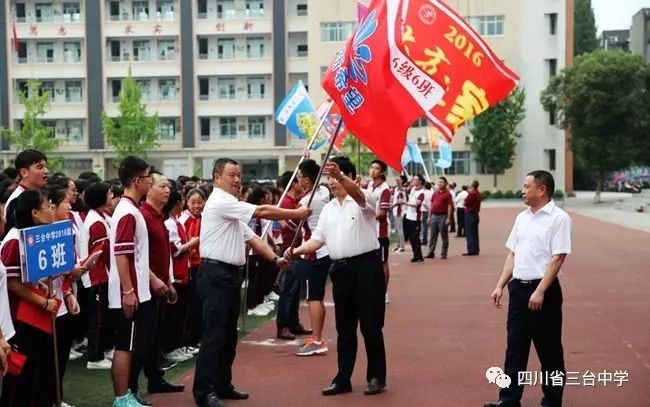 校长曹福文,书记龙旭桄,副校长刘文明分别为三个年级授班旗,其后为三