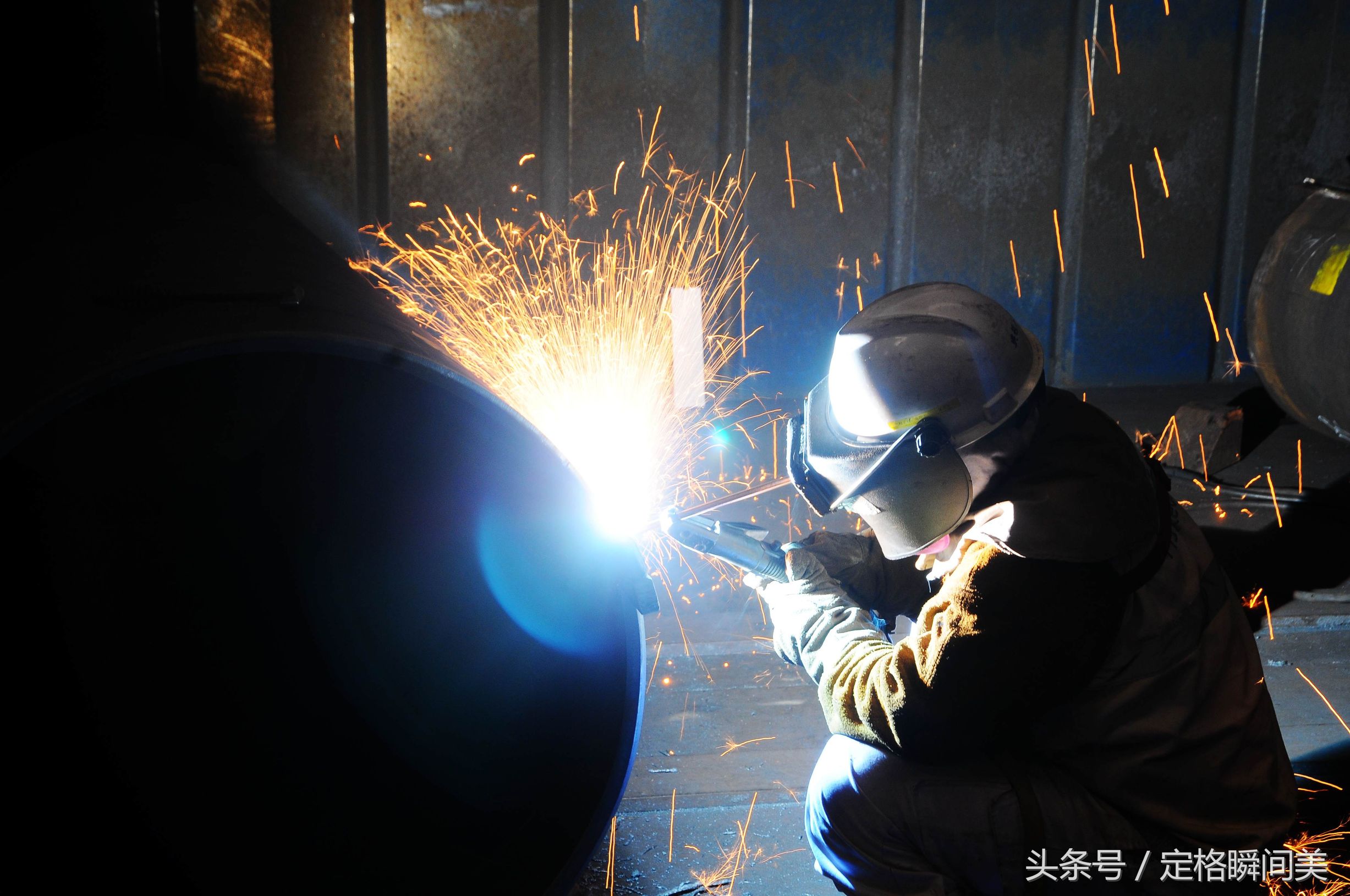 图为:船舶重工企业里,一名电焊工人在焊接作业中.