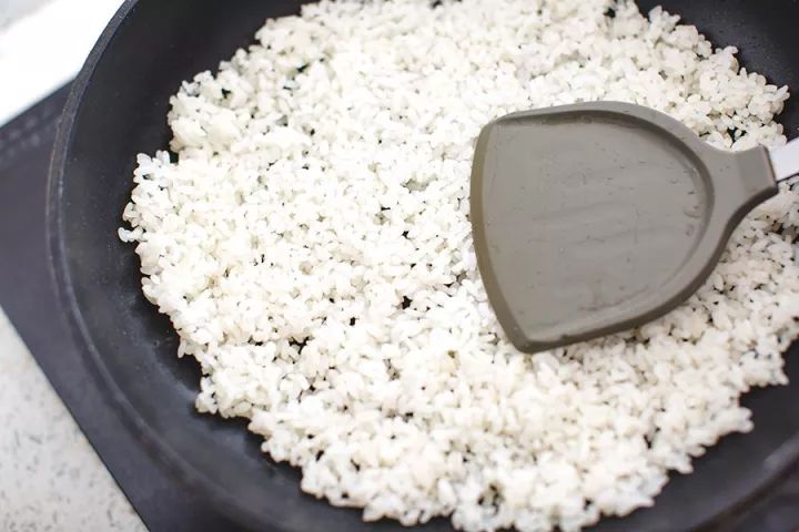 1.压米饼:把熟米饭倒入锅中,压成米饼状.