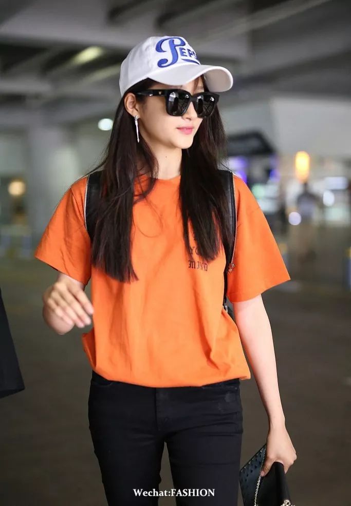 橘色t恤搭配黑色牛仔裤,脚踩金色运动鞋,头戴棒球帽,活力不失潮味.