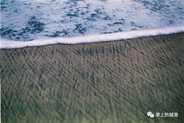 而在防城港 却有一个很特别的沙滩——白浪滩 幼滑的细沙 黑沙白浪