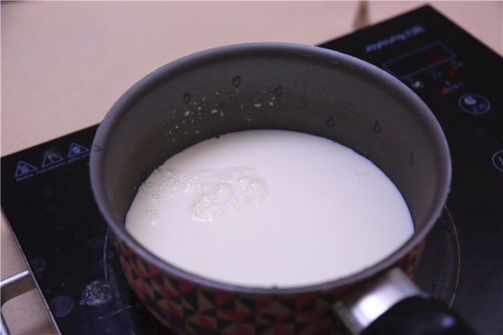 ③将牛奶用奶锅煮开,然后将热牛奶缓缓倒入蛋黄面糊中,边倒边搅拌