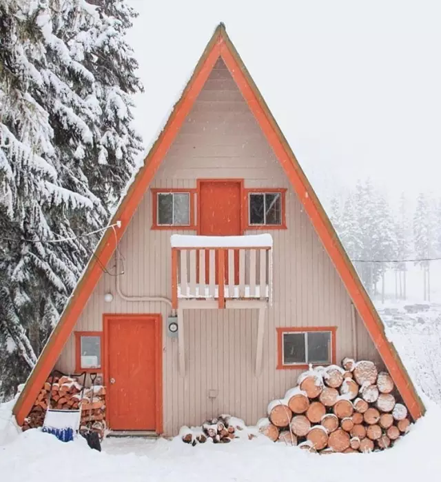 橘色的小木屋,在白雪的映衬下显得更可爱,门口堆着的木头,大约就是为