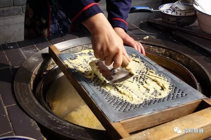 把面团从抿节床上擦到开水锅里.