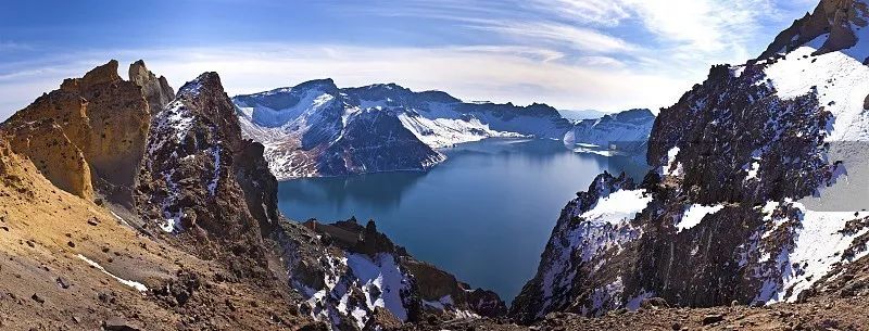 长白山天池是一座休眠火山,火山口积水成湖,夏融池水湛蓝;冬冻冰面