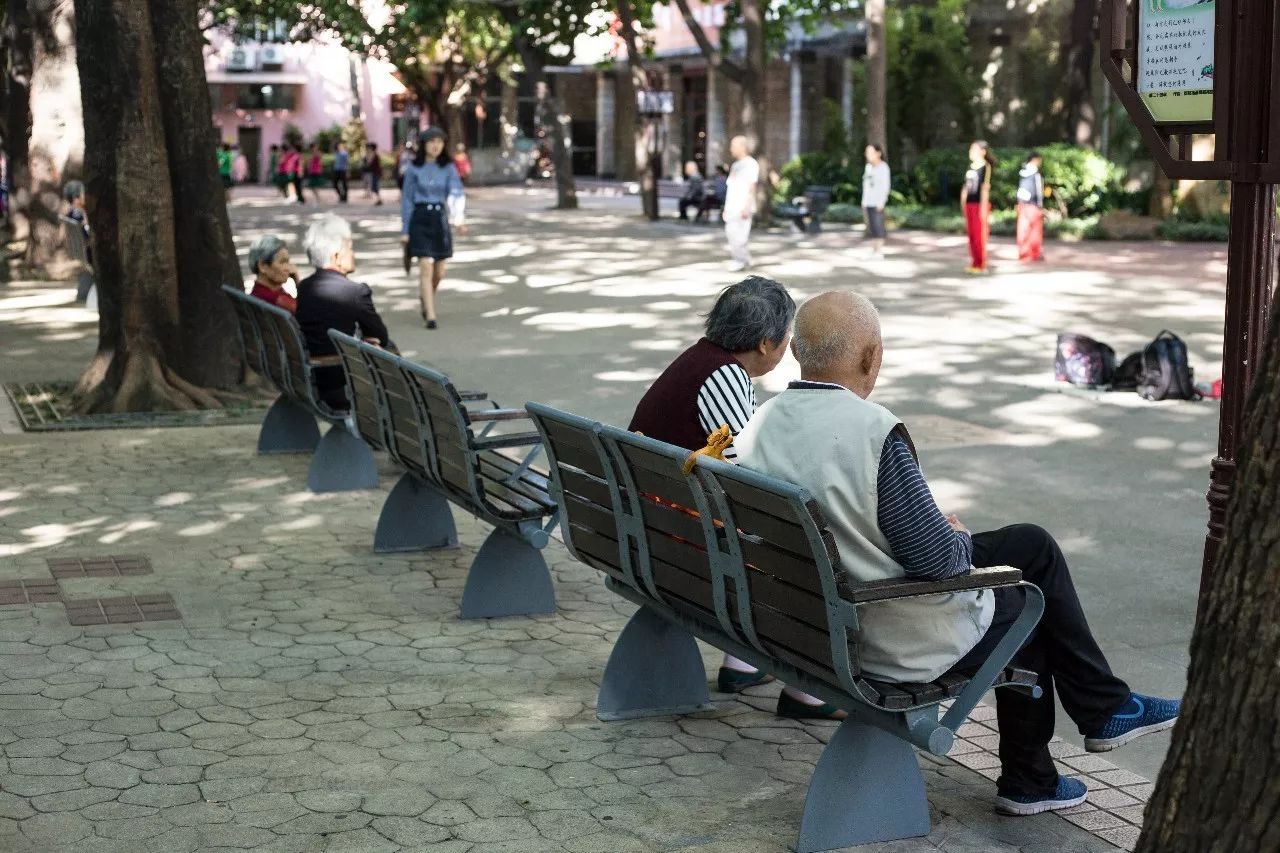 公园里,老人们相约散步,累了就在长椅上聊聊天.