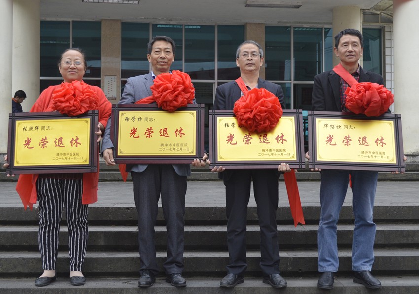 最后四位退休职工胸戴大红花,手捧"光荣退休"牌匾,与医院领导和同事