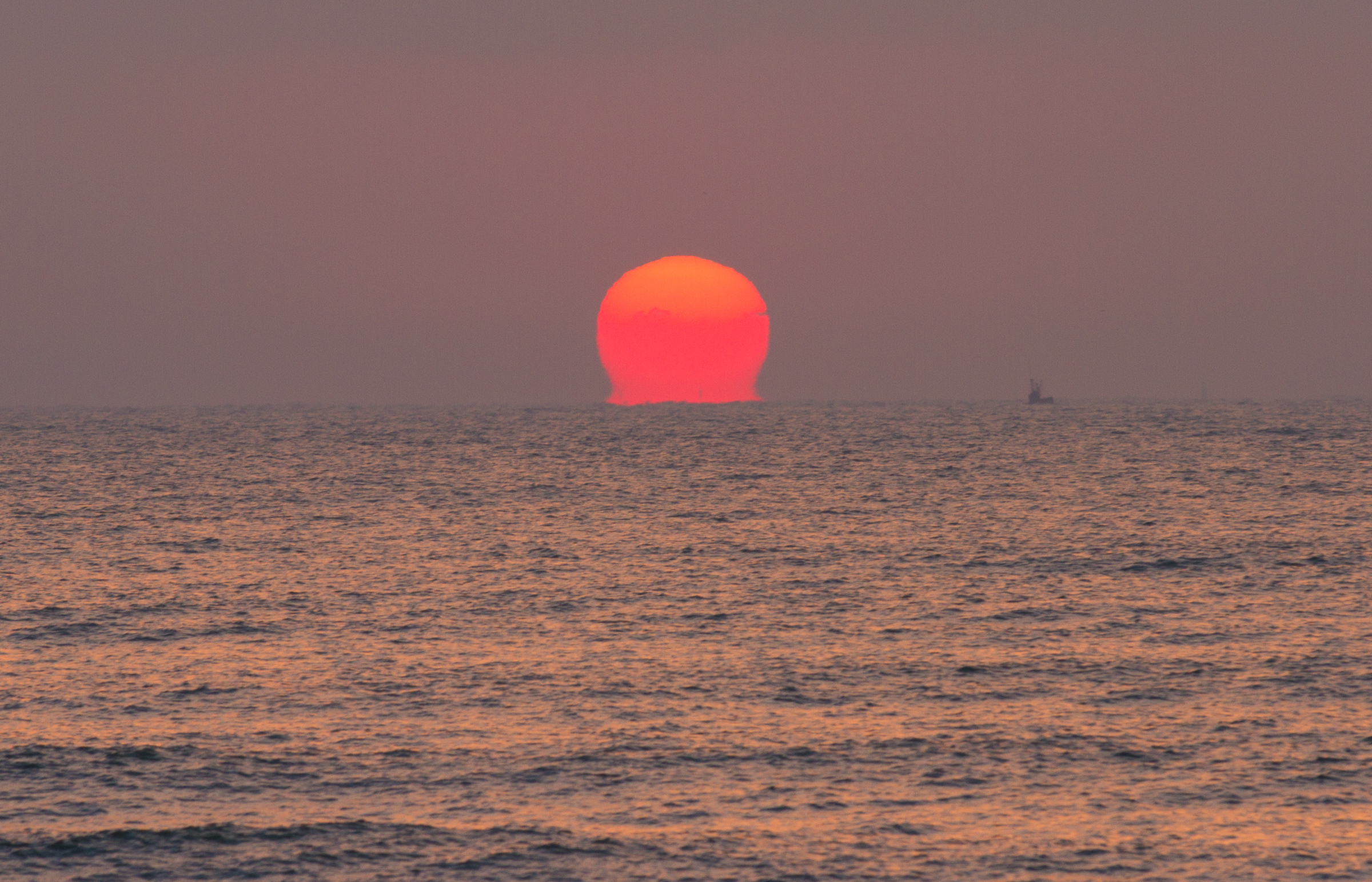 红太阳和海面好似粘连,震撼的视觉效果.