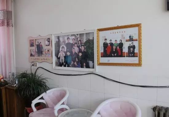 刘建民家的客厅墙上挂着的全家福照片和"乐亭县最美家庭"荣誉证书.
