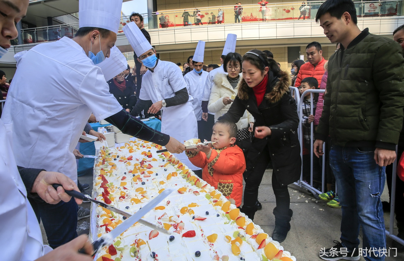 12月31日,市民在庐江县一家大型商场的广场上免费品尝巨无霸蛋糕,甜