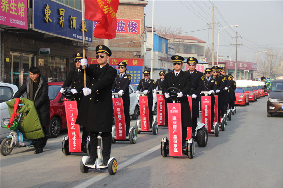 建业物业21名工作人员身着西装墨镜组成的平衡车方阵吸引了沿路大批