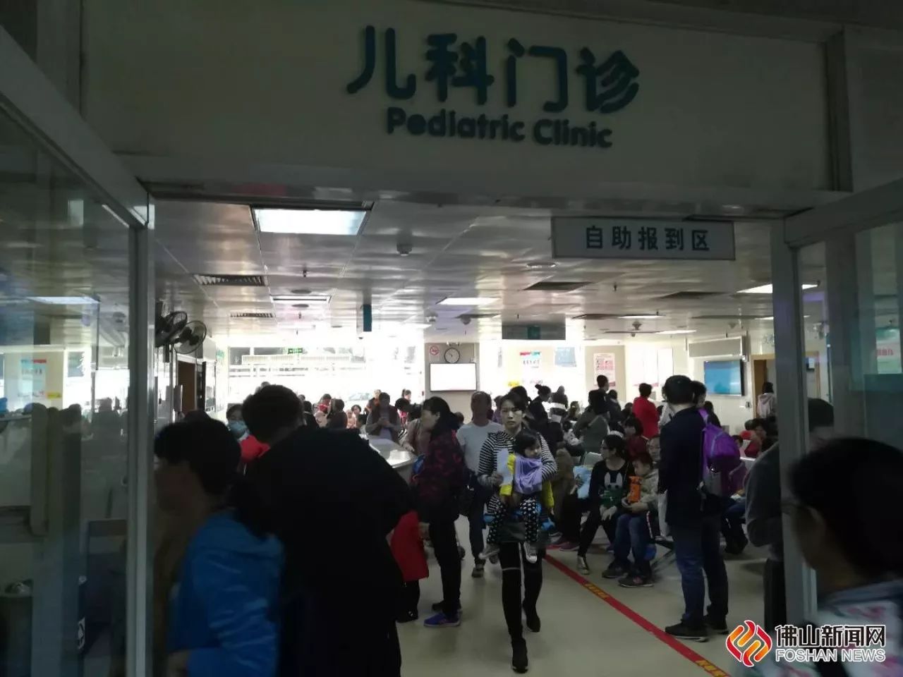 市妇幼医院儿科门诊内很多家长带着小孩在候诊.