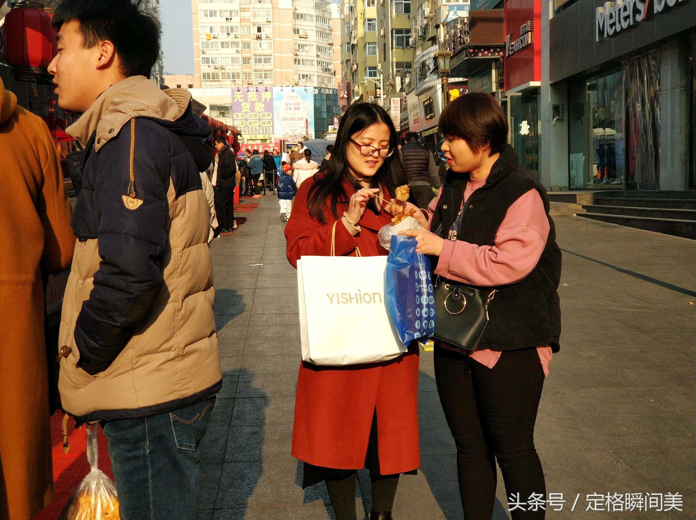 图为:冬日里台东步行街上,两位美女在分享各种小吃.