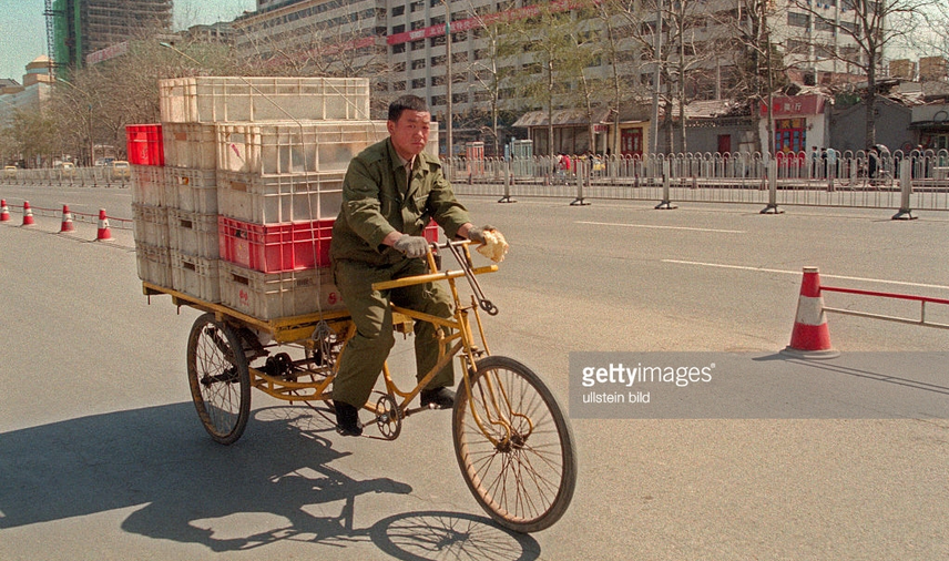 90年代北京历史老照片:图为一个工人骑着一辆三轮车载着一车的塑料