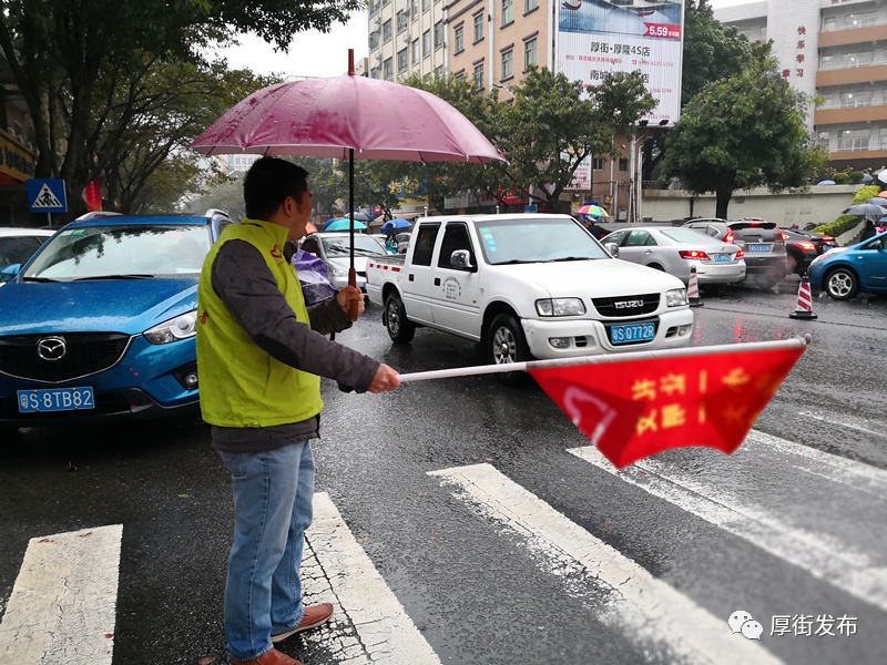 志愿者摇旗指挥车辆,让小学生们安全走过斑马线