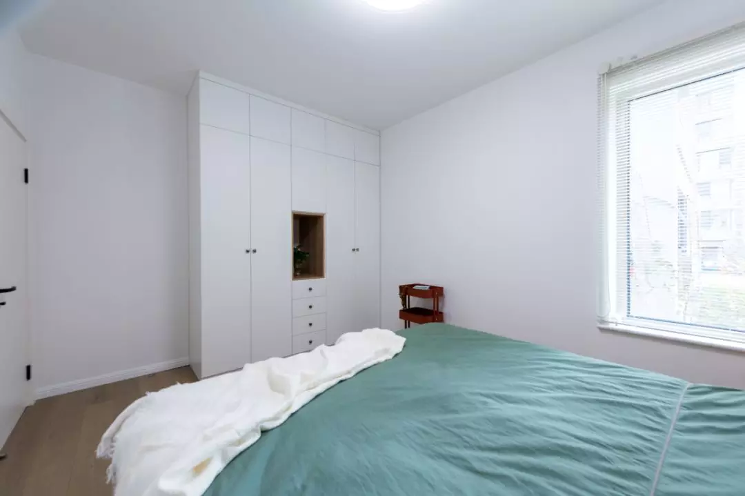 床的对面设计了纯白的衣柜,配合原木色的壁龛,与雪白的墙壁融为一体.