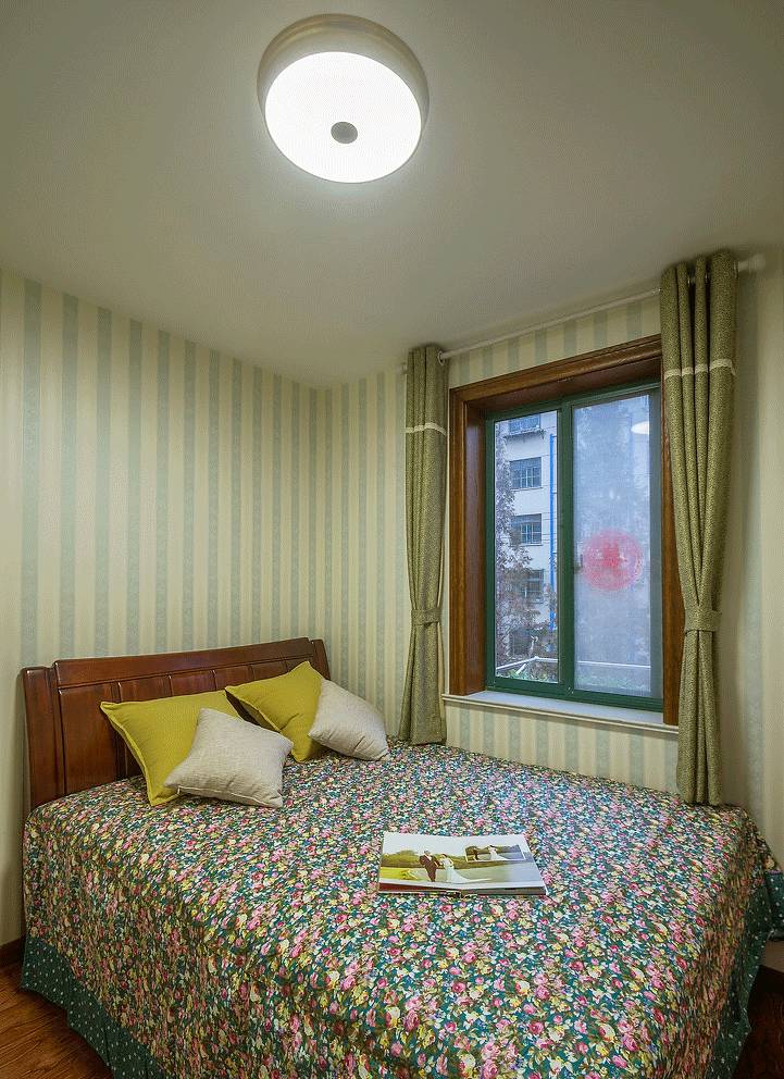 次卧面积小点,床紧挨着窗户,十分温馨,墙面用墙纸装饰,也符合整体