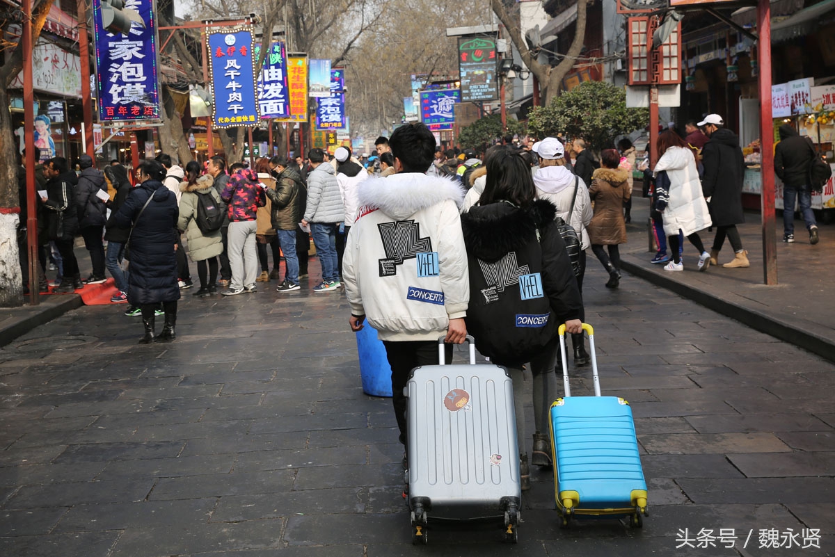 放假了大学生情侣穿情侣装拉着行李直奔回民街