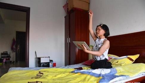 下课回家后,蒋张子怡在床上利用平板电脑学习舞蹈.