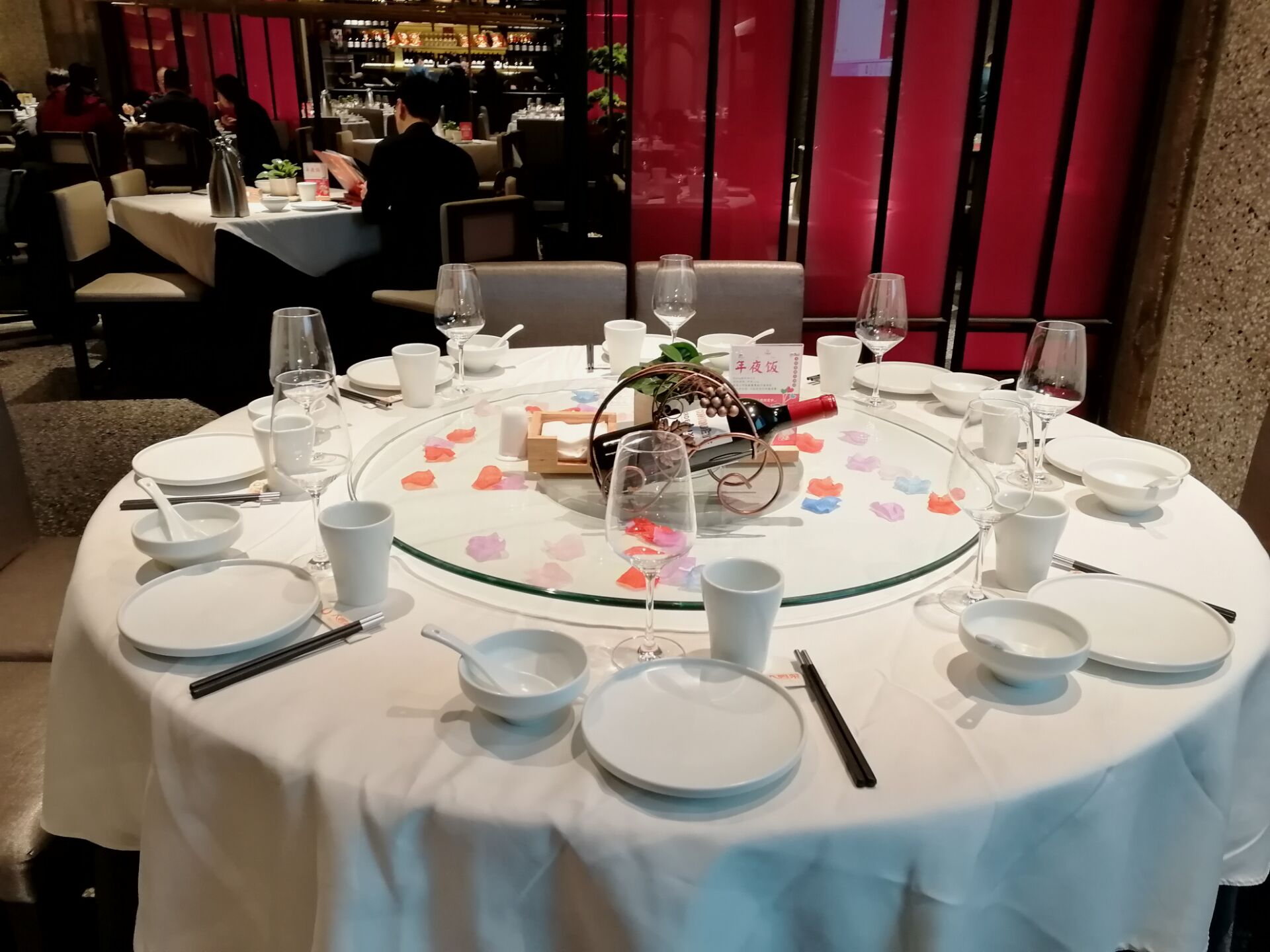 整洁的餐桌,雪白的餐具,转盘下的花瓣摆设显然增加了不少生机