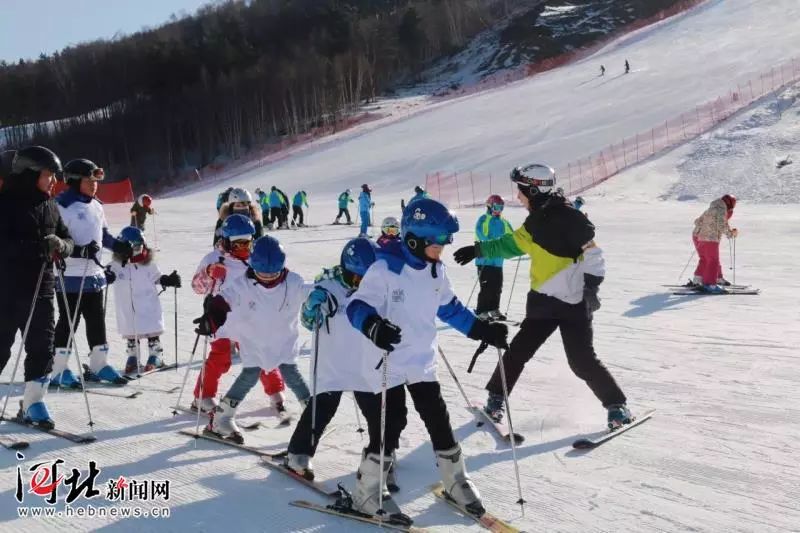 参加冰雪冬令营活动的孩子们在教练指导下练习滑雪.