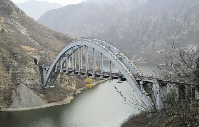 从高高的山上看去 铁桥横跨在珍珠湖两岸的山崖上 半圆形的桥拱 很