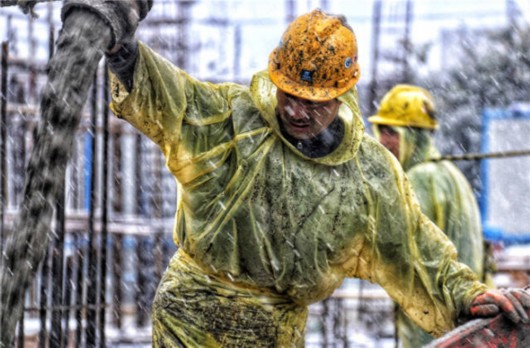 1月25日,建筑工人冒着风雪在上海一市政工程工地进行混凝土浇注施工.