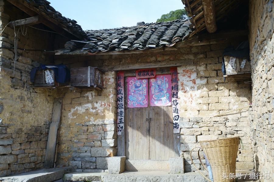 土砖房,大门上贴着对联和年画,墙壁上还挂着蜂笼.
