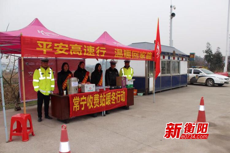 收费站附近路边立着一个铝合金雨蓬,写有"暖冬行动"字样的红色横幅