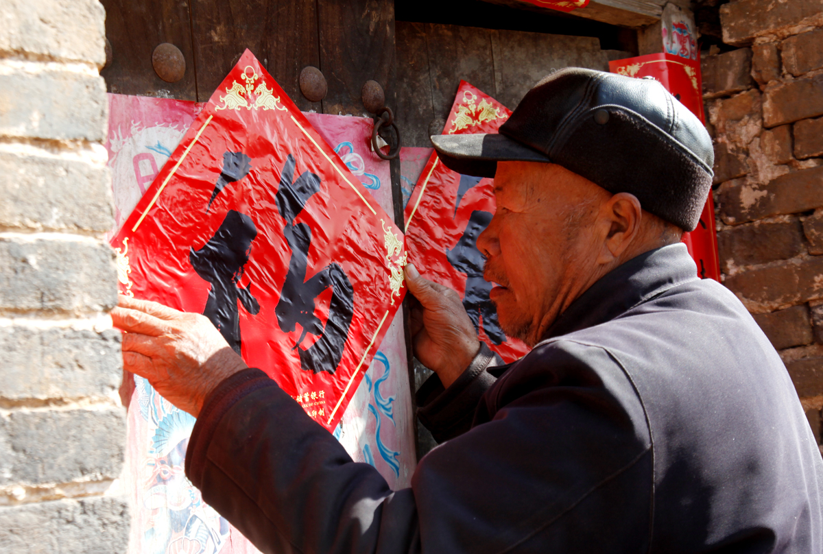豫西山村八十二岁的老伯,腊月二十八站在梯子上贴年画