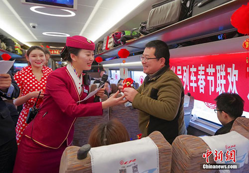 图为在答问互动环节,列车长官淼向答对问题的乘客发狗年吉祥物礼品.