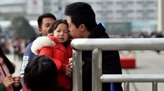 奶奶抱着孙女来车站送儿子儿媳出去打工,孩子看着爸爸妈妈进站,伤心地