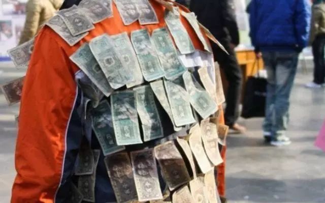 男子身上贴满纸币在大街上闲逛，路人纷纷围观，有人出千元收藏