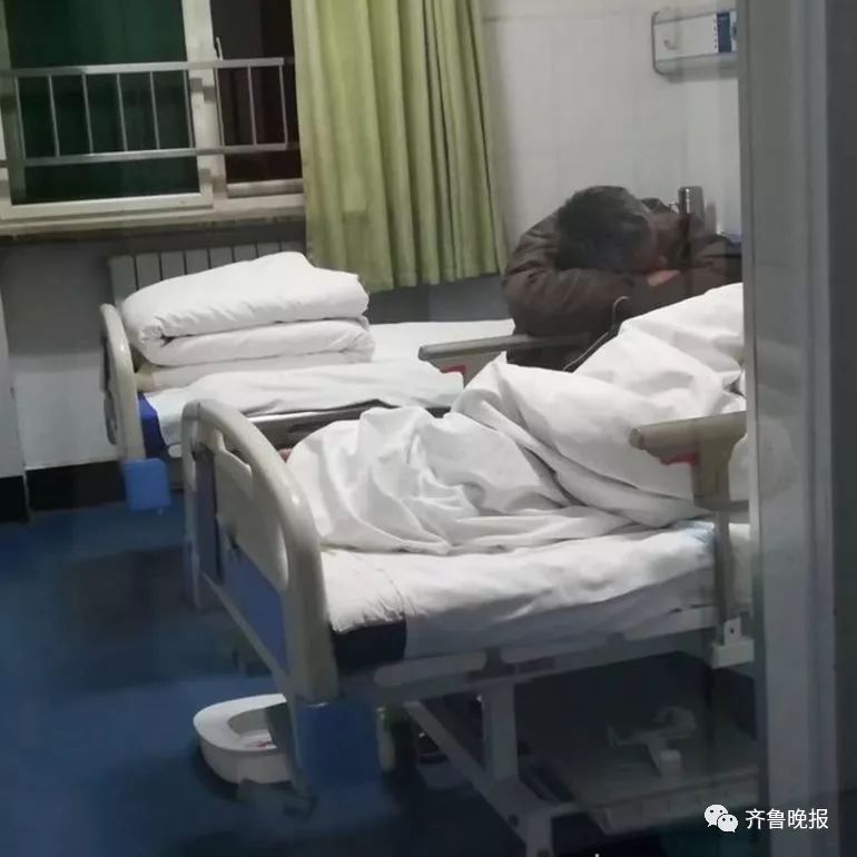 一位头发花白的男子正趴在病床前陪守病人.