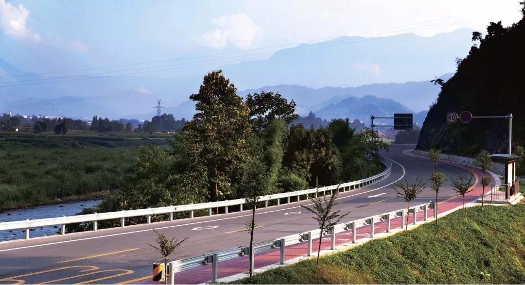 湔江路蜿蜒的道路,湛蓝的天空,沿途村庄,森林,沟壑隐隐可现,春季山花