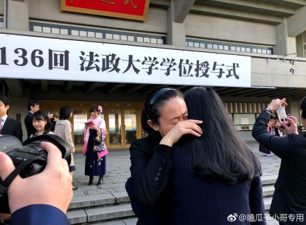 照片中江秋莲手捧女儿遗像,站在写有"法政大学学位授予式"的横幅下.