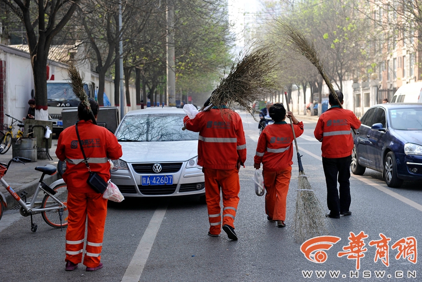 西安市西工大路上,4名环卫工人刚刚打扫完早市,扛着扫帚回家.