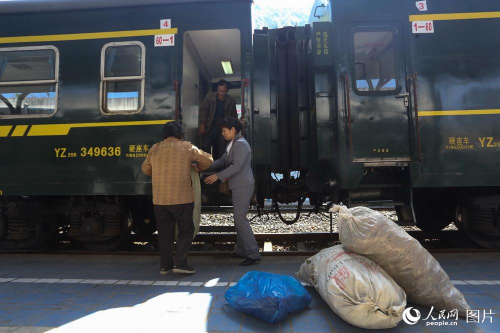 5630次列车员正在帮助旅客上车,在川黔线上,背篼已成为一道独特的风景