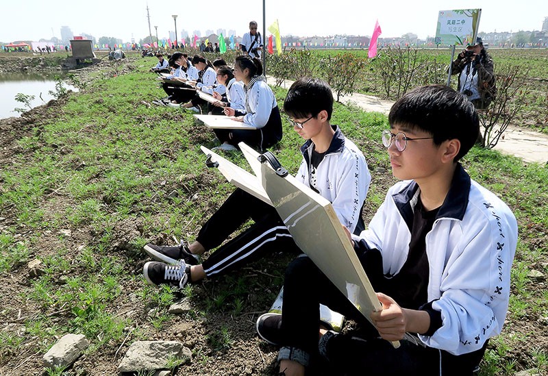 图为一群中学生美术爱好者在现场写生.