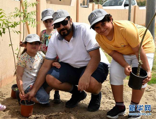 4月21日,在巴林首都麦纳麦,一名巴林人带着孩子们植树.22日是世界