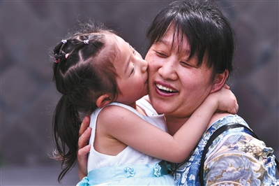 5月13日,成都市街头,一位小女孩亲吻妈妈.图/视觉中国