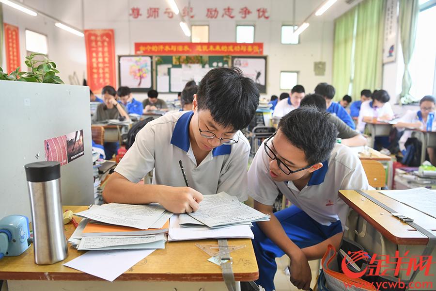 广大附中,两名学生在讨论试题.大扇子成为消暑静心的助考神器.