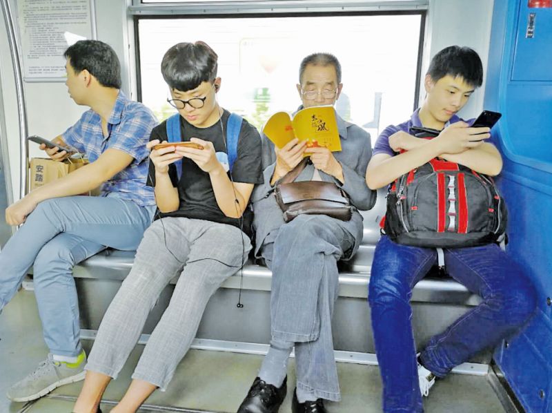 老年人看书,年轻人低头玩手机.